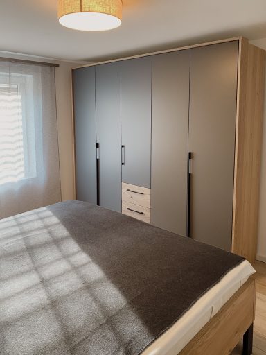 GERÄUMIGER KLEIDERSCHRANK Schlafzimmer mit einem Bett und einem modernen, hellen Kleiderschrank.